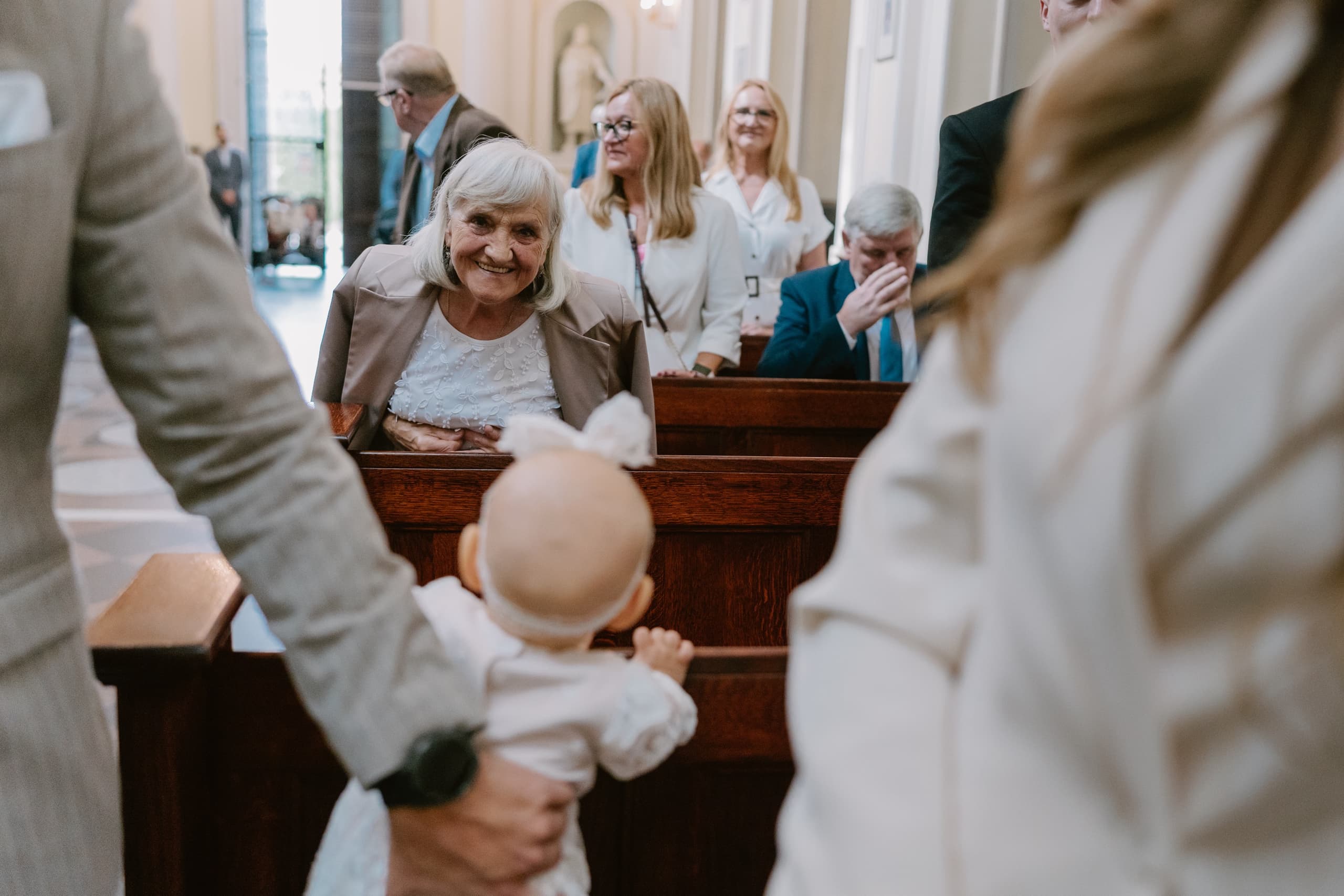 Babcia uśmiecha się do niemowlęcia w kościelnej ławce podczas chrztu